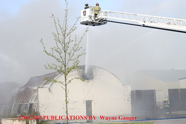 firemen battle a fire in a corrugated steel building