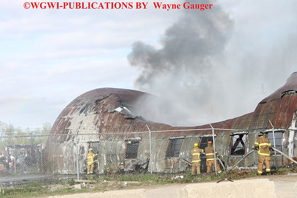 firemen battle a fire in a corrugated steel building