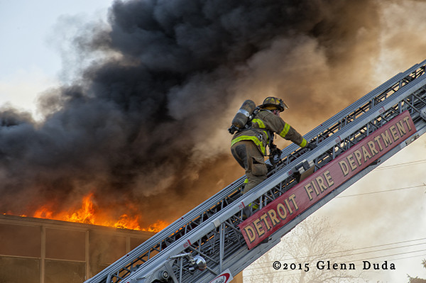 Detroit fireman climbing aerial ladder with smoke and flames