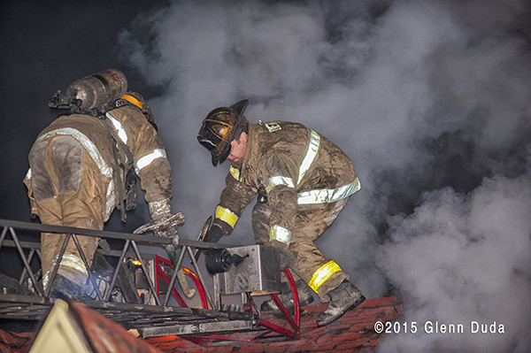 firemen on roof with heavy smoke at night