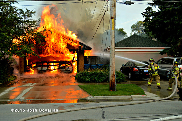 firemen battle a garage fully engulfed in flames