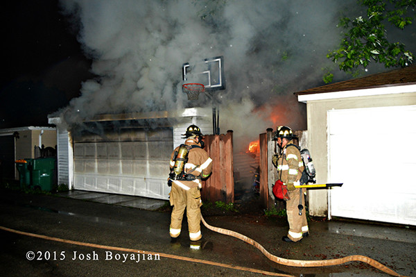 firemen attack fire in an alley garage at night