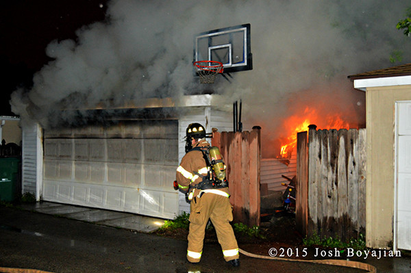 firemen attack fire in an alley garage at night