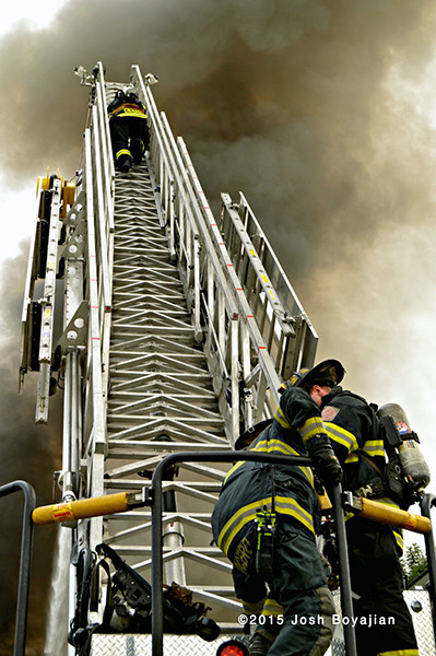 fireman climbs E-ONE aerial ladder at fire scene