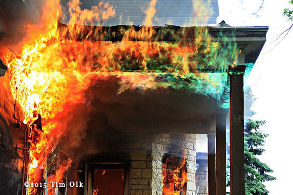 flames roll along porch of burning house