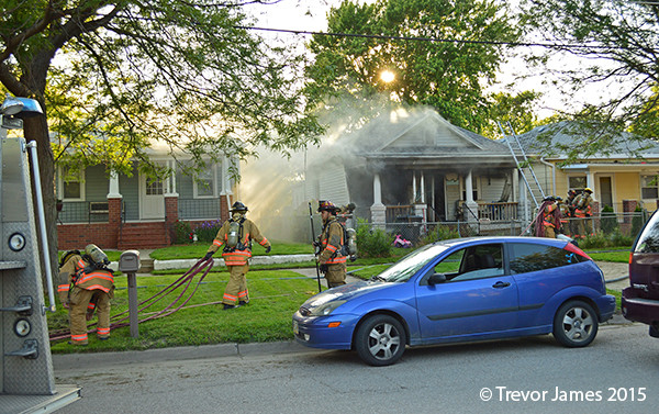 fireman drags hose line to fight house fire