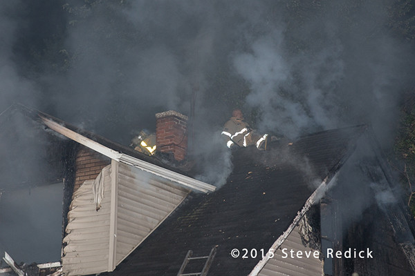 fireman on roof of house fire at night