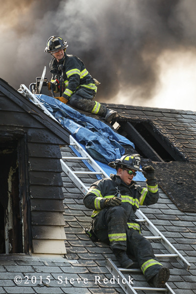 firemen on roof of house with salvage tarp