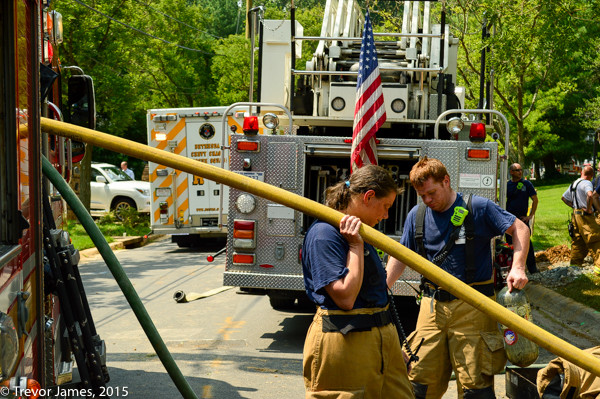 female firefighter picks up hose after fire