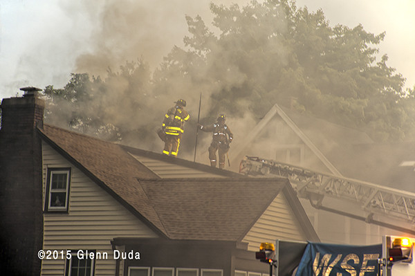 firemen in smoke on roof of house fire