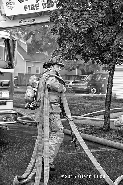 fireman pulling hose at fire scene
