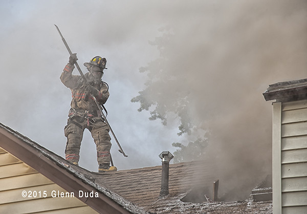 fireman in smoke on roof of house fire