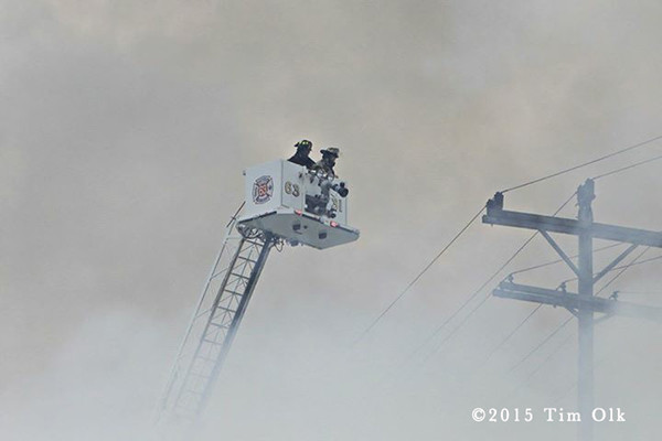 firemen in tower ladder platform with heavy smoke