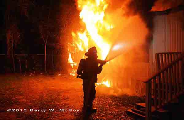 firefighter with hose silhouetted by flames