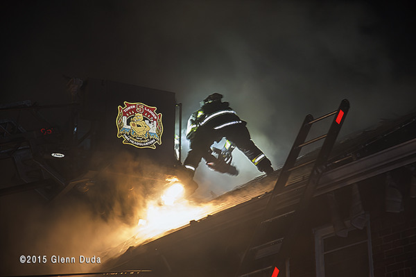 firefighter vents roof at night fire