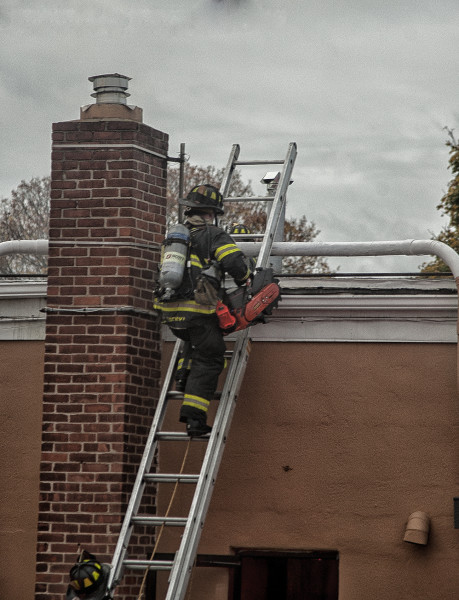 firefighters vent the roof of a strip mall during a fire