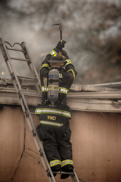 firefighters vent the roof of a strip mall during a fire