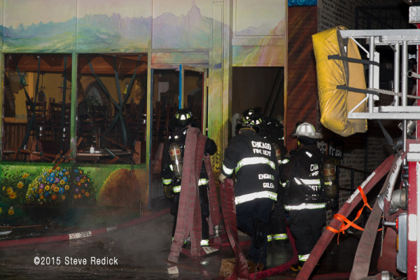 firefighters carry hose at night fire scene