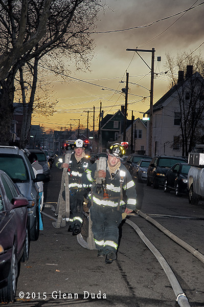 firemen carry hose at dawn