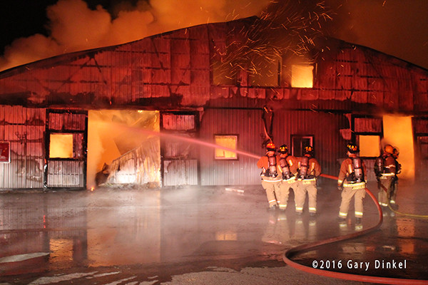 firefighters battle a horse stable fire at night in the winter