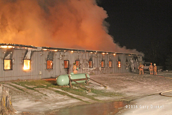 firefighters battle a horse stable fire at night in the winter