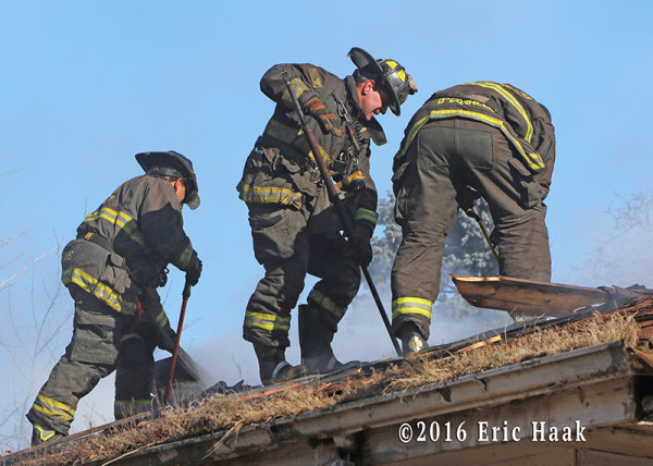 firemen vent roof at house fire