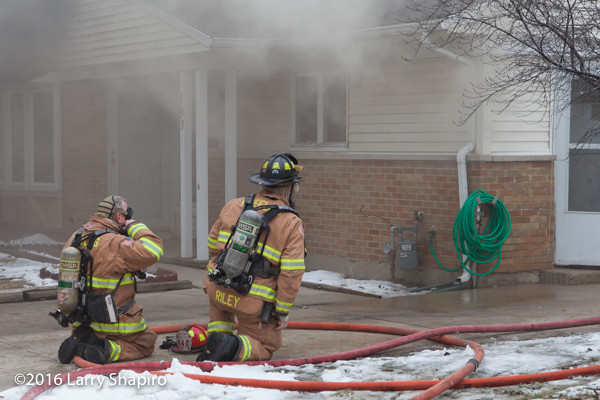 firemen prepare to enter house on fire