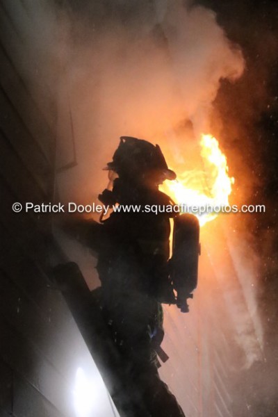firefighter on ladder at night with flames