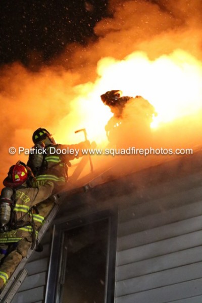 firefighters on roof of house at night with flames