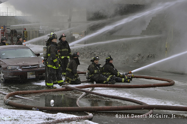 firefighters with hose lines at fire scene