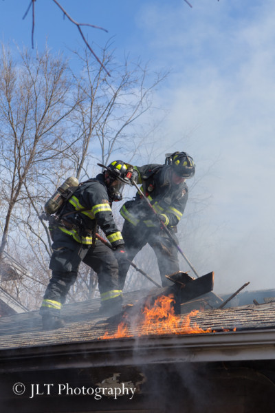firemen on roof of house fire
