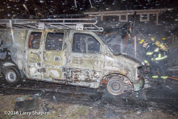 burned shell of a delivery van next to a house
