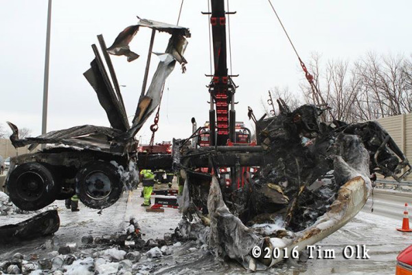 heavy wrecker tow truck from Ernie's Wrecker service lifts charred remains of a truck
