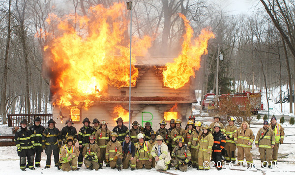 firefighters pose with burning house after training
