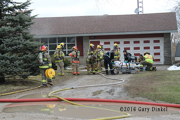 firefighters and EMS personnel attend to a victim of a house fire