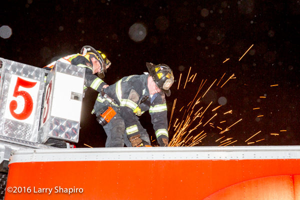 fireman uses a saw to cut semi trailer