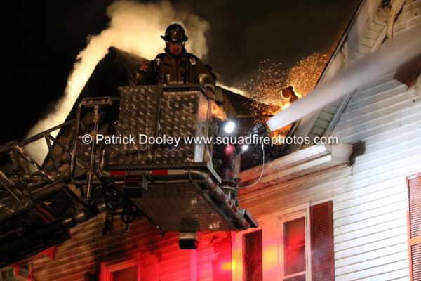 firefighters in tower ladder at night fire scene