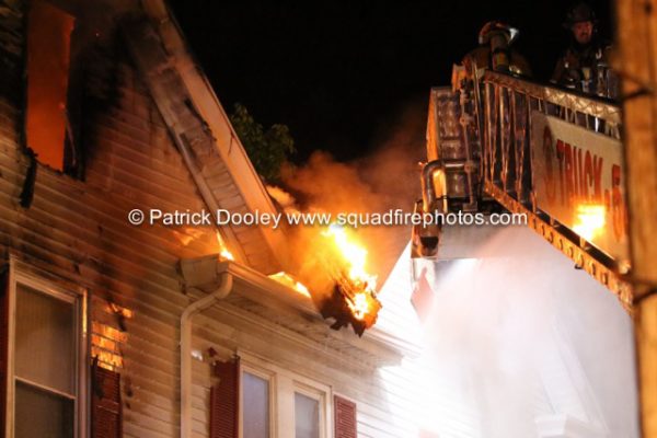 firefighters in tower ladder at night fire scene