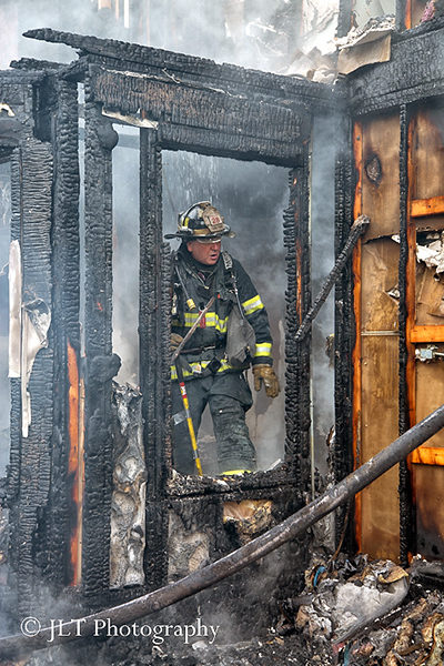 firefighter inspects house fire aftermath