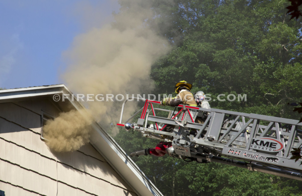 firefighter on aerial ladder tip at house fire