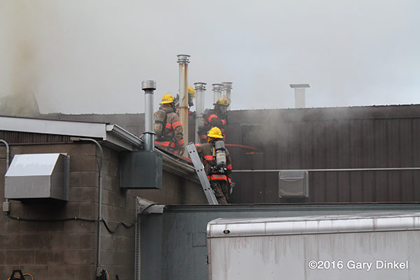 firefighters on building roof with smoke