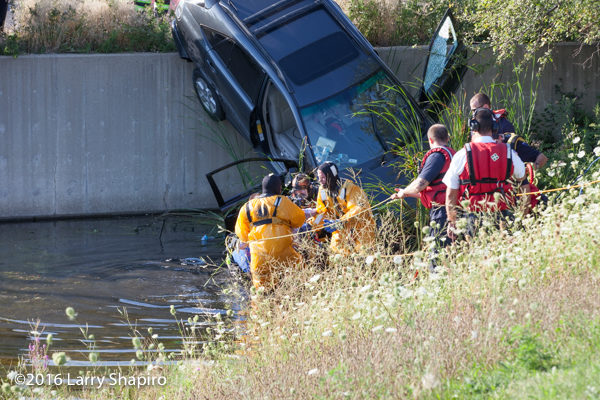 fire department divers rescue the driver from a car on a retaining wall 