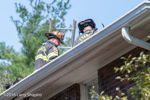 firefighters on roof of house fire