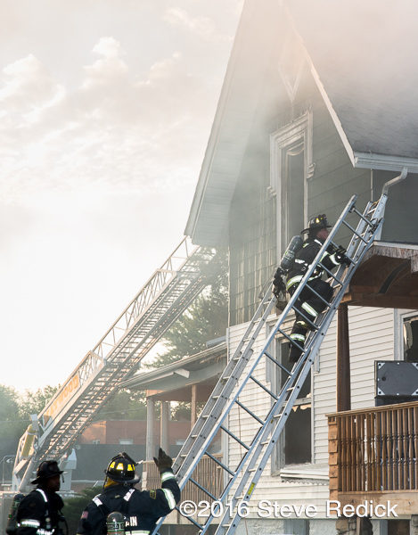 firefighters carry ladders at house fire