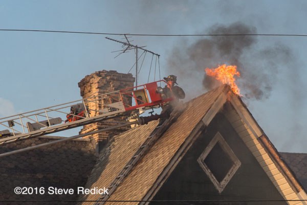 firefighters on aerial ladder tip fire flames