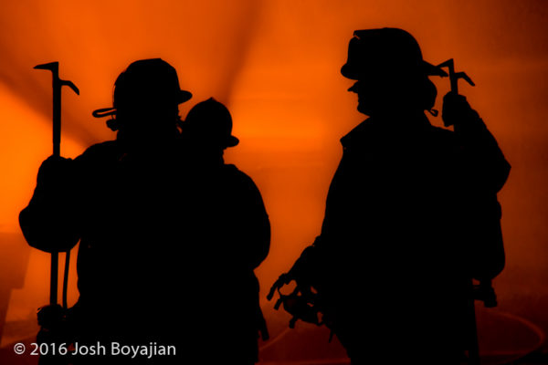 silhouette of firefighters by house fire