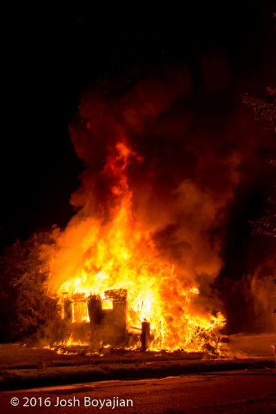 vacant house fully engulfed in flames at night