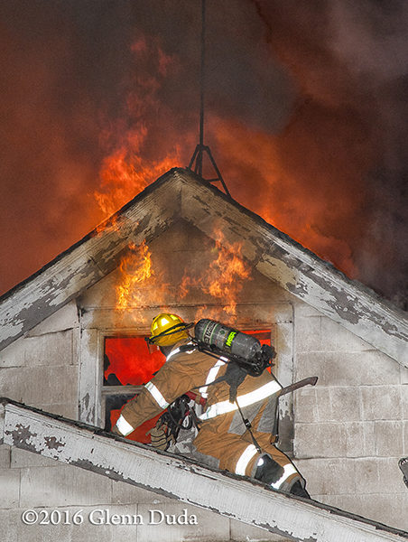 firefighter on roof with heavy fire