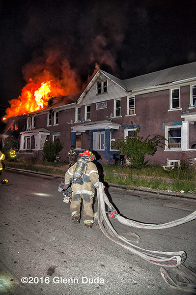 firefighter lays out hose at night fire scene