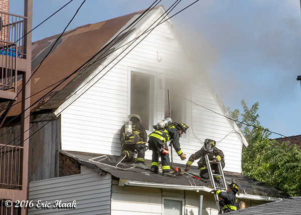 firefighters on roof of house with smoke